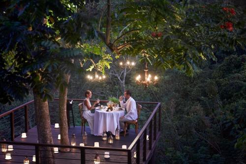 two people sitting at a table on a deck at night at Kamandalu Ubud - CHSE Certified in Ubud