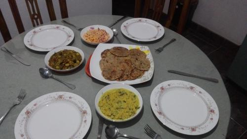 a table with plates and bowls of food on it at Mango Roots in Gampaha