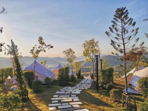 un sentiero in pietra con alberi e montagne sullo sfondo di Papa Garden Khaokho a Khao Kho