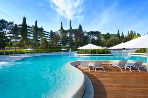 a large swimming pool with chairs and umbrellas at Eden Hotel by Maistra Collection in Rovinj