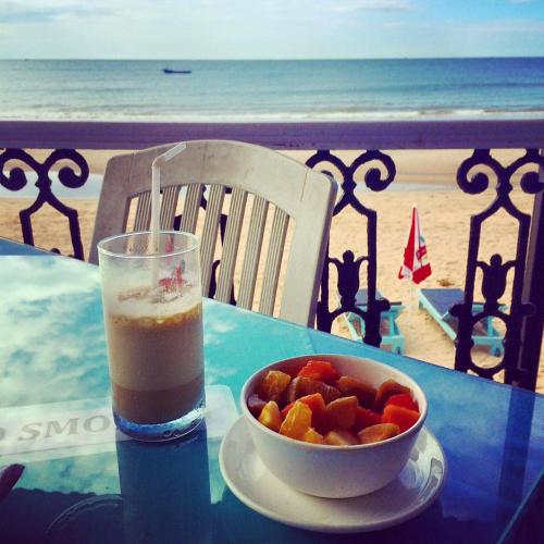 a drink and a bowl of fruit on a table with the beach at Joets Guesthouse in Bogmolo