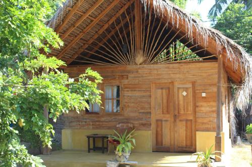a wooden cabin with a thatched roof and a door at Margarita Village kite school kalpitiya in Kalpitiya