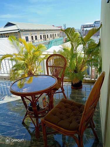 a table and chairs on a balcony with palm trees at KOL House in Phnom Penh