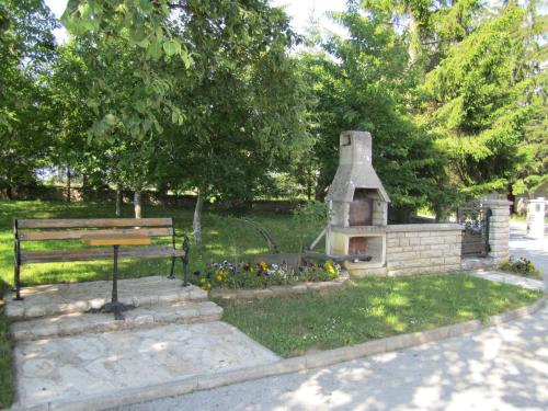 a park with a bench and a fireplace in the grass at Guest House Sveti Marko Gacka in Otočac
