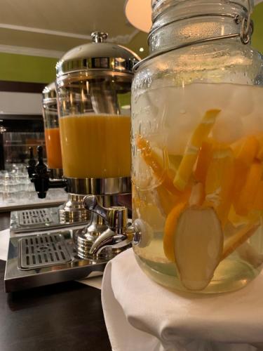 a glass jar filled with orange juice next to a juicer at Hotel Bentheimer Hof in Bad Bentheim