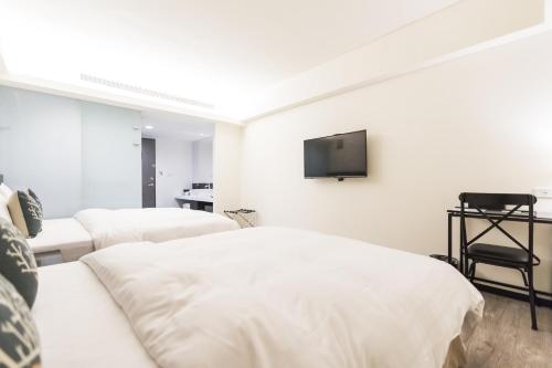 a bedroom with two beds and a tv on the wall at Home Rest Hotel in Taitung City