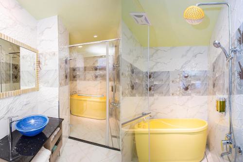 a bathroom with a shower and a yellow tub at Diudiu Dang Paternity B&B in Dongshan