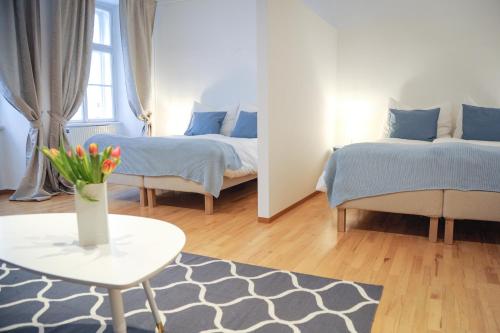 City Center Apartment في فيينا: غرفة نوم بسريرين وطاولة مع إناء من الزهور