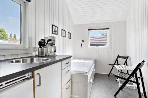biała kuchnia ze zlewem i oknem w obiekcie Omme Å Camping & Cottages w mieście Sønder Omme