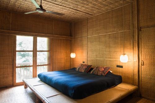 Un dormitorio con una gran cama azul y una ventana en Lisu Lodge, en Mae Taeng