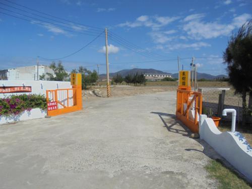 a parking lot with an orange gate in a field at 象樹園農莊特色民宿 in Checheng