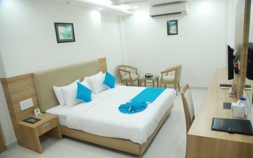 a bedroom with a bed with blue pillows at Hotel Anjali Park in Kottayam