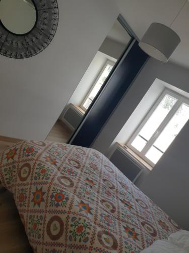 a bedroom with a bed and two windows at APPARTEMENT ROUGE in Saint-Anthème