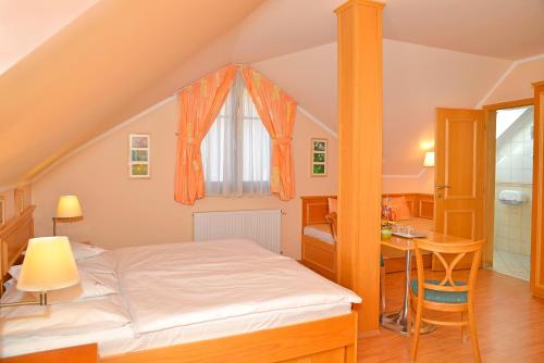 a bedroom with a bed and a desk and a window at Vadászkürt Panzió és Étterem in Sopron