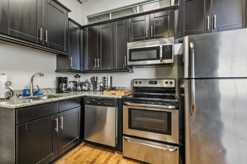 a kitchen with stainless steel appliances and black cabinets at Gorgeous Condos - Walk to French Quarter in New Orleans