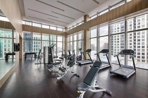 a gym with cardio equipment in a large room with windows at Pavilion Hotel Kuala Lumpur Managed by Banyan Tree in Kuala Lumpur