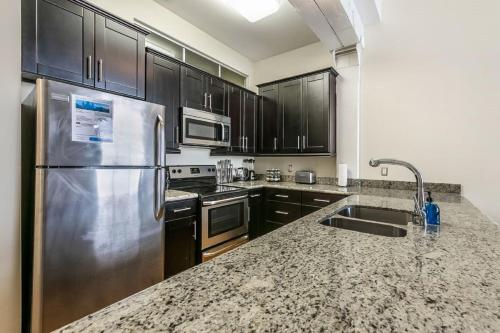 a kitchen with black cabinets and a stainless steel refrigerator at Beautiful Condos Steps from French Quarter and Bourbon St in New Orleans