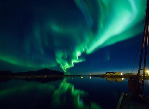 an aurora in the sky over a body of water at Beach View Lofoten in Bøstad
