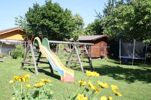 a playground with a slide in a yard with flowers at Pension-Ferienwohnung Rotar in Faak am See