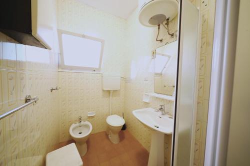 a white bathroom with a toilet and a sink at Villetta Botticelli in Lido di Spina