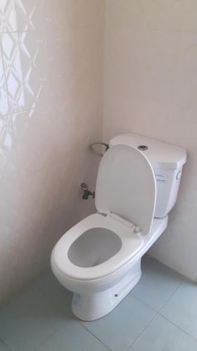 a bathroom with a white toilet in a room at Appartement familial spacieux avec climatisation in Ziguinchor