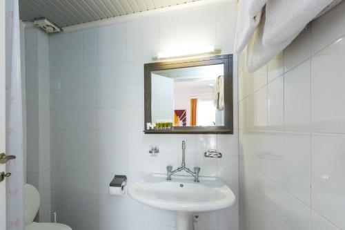 Baño blanco con lavabo y espejo en Castello Bianco Aparthotel en Platanés