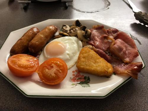 a plate of breakfast food with eggs bacon and tomatoes at Melrose cottage in Goring