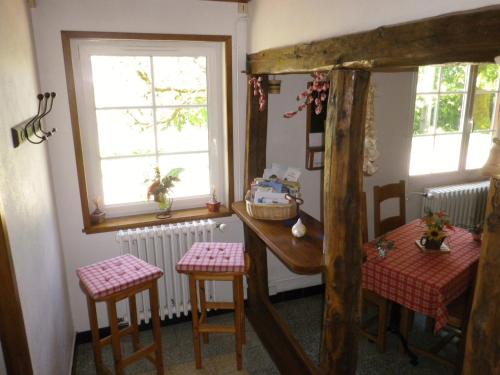 a room with a table and two chairs and two windows at Chambre d'hôtes La Haie Fleurie in Chevillard