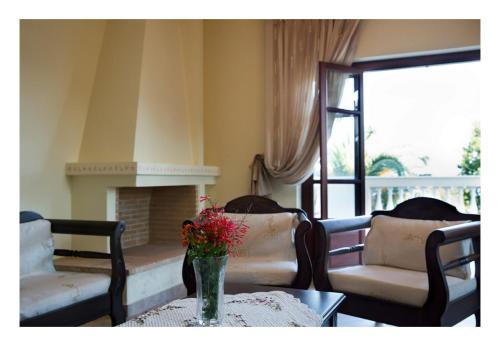 a living room with a fireplace and a table with flowers at Alonissos beach villa 5 steps away from the sea in Kalamakia