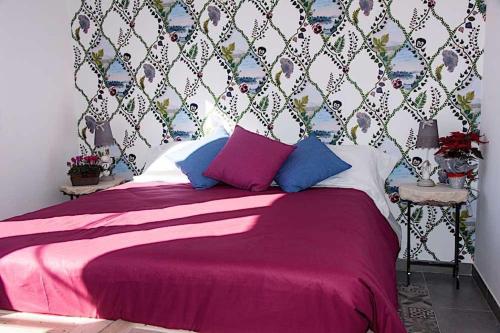a bedroom with a bed with pink sheets and blue pillows at Agriturismo Cozzo di Papaleo in Ragusa