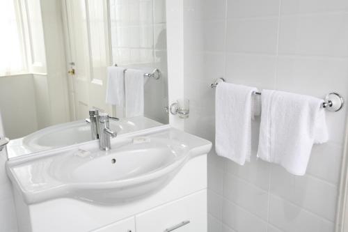 a white bathroom with a sink and towels at Clifton Hotel in Glasgow