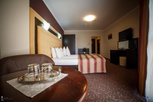 a hotel room with a bed and a table with glasses on it at Hotel Ozana in Bistriţa