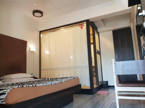 a bedroom with a bed with a curtain and a chair at Hotel Milan International in Mumbai