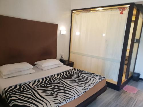 a zebra print bed in a room with a window at Hotel Milan International in Mumbai