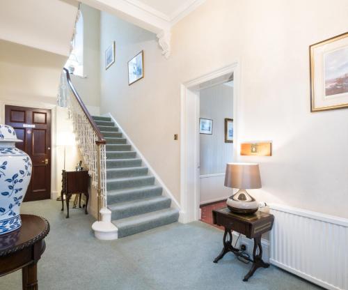 a hallway with stairs and a table with a lamp at Sunbank House Metro Hotel in Perth
