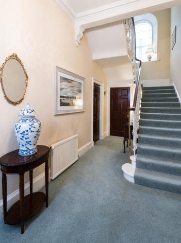 a hallway with stairs and a vase on a table at Sunbank House Metro Hotel in Perth