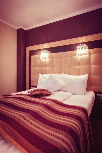 a bedroom with a large bed with purple walls at Hotel Ozana in Bistriţa