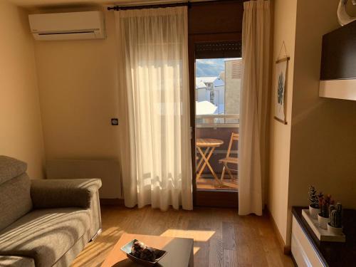 a living room with a couch and a door to a balcony at Apartament Neret I in Sort