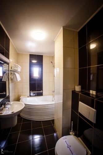 a bathroom with a tub and a toilet and a sink at Hotel Ozana in Bistriţa