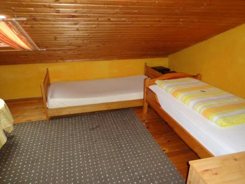 two beds in a small room with wooden walls at Pension Schamberger in Neukirchen beim Heiligen Blut