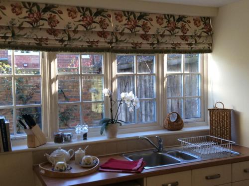 a kitchen with three windows and a sink and a sink at Freshwater Barn in Benenden