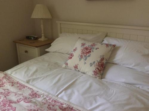 a white bed with a floral pillow on it at Freshwater Barn in Benenden