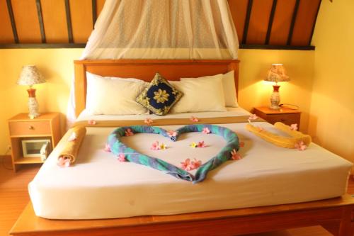 a bedroom with two beds with a heart shaped bed at Bedolo Bungalows in Gili Air