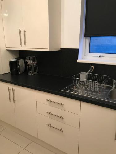 a kitchen with white cabinets and a black counter top at Liverpool townhouse in Liverpool