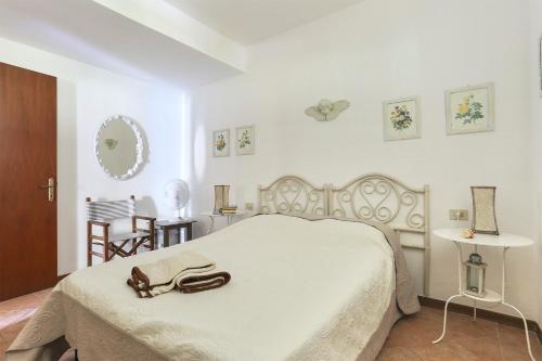 a white bedroom with a large white bed with a brown purse on it at Soleado beach house in Pietrasanta