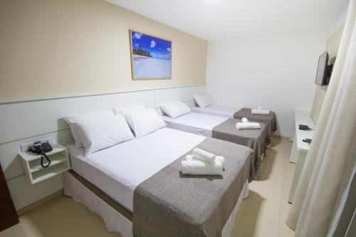 Una habitación con tres camas con toallas. en Pousada Kanoas, en Maragogi
