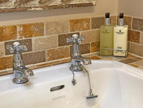 a sink with two faucets and two bottles of soap at Ivy Cottage in Laxton