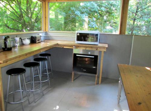 eine Küche mit einer Theke mit Hockern und einer Mikrowelle in der Unterkunft Evergreen Cabin Karkloof in Yarrow