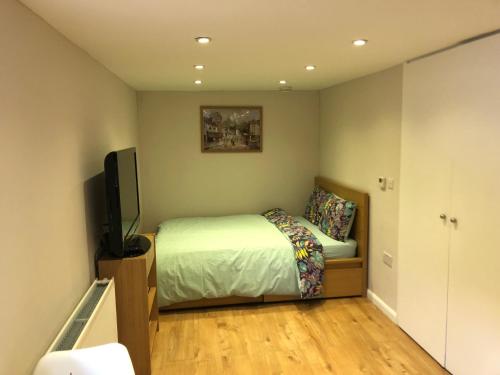 a bedroom with a bed and a flat screen tv at Agars Place, Datchet in Datchet