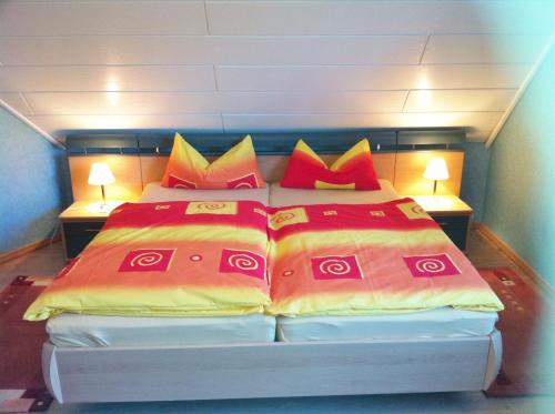 - une chambre avec 2 lits dotés d'oreillers rouges et jaunes dans l'établissement Ferienwohnung Grün, à Schweigen-Rechtenbach